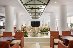 hol ze stołami i krzesłami oraz basenem w obiekcie Welikehotel Marfil Playa w Sa Coma