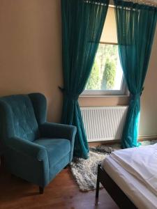 a bedroom with a blue chair and a window at Aleu - Apuseni Mountains in Pietroasa
