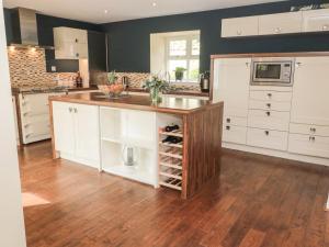 a kitchen with white cabinets and a wooden counter top at Calm Skies in Berwick-Upon-Tweed