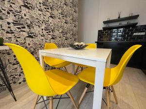 a dining room with a white table and yellow chairs at A5 Apartment - Budapest - hostAID in Budapest