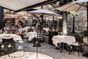 un restaurante con mesas blancas, sillas y sombrillas en La Casa del Presidente, en Ávila
