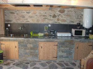 a kitchen with a stone counter top with a microwave at Casa Capela - Casas do Sinhel in Alvares
