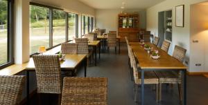 un restaurante con mesas y sillas de madera y ventanas en Hotelet Del Bac en Camprodon