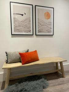 a wooden bench sitting on a wall with three pictures at Brand new 3-bedroom home in London in London