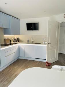 cocina con armarios blancos y TV en la pared en Hampton Vale, Peterborough Lakeside Large Double bedroom with own bathroom en Peterborough