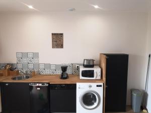 a kitchen with a washing machine and a microwave at L'Annexe in Charron
