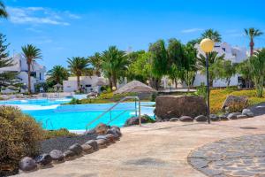 a swimming pool in a resort with palm trees at Los Molinos Luxury y Relax in Costa Teguise