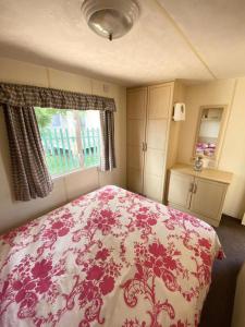um quarto com uma cama rosa e branca e uma janela em 604 Seawick em Jaywick Sands