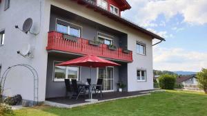 ein Haus mit einem Tisch und einem roten Regenschirm in der Unterkunft Urlaub am Sonnenhügl in Rinchnach