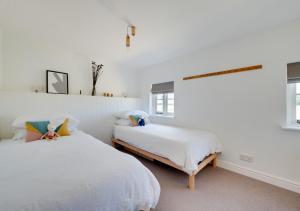 two beds in a room with white walls and windows at Fairstead in Spexhall