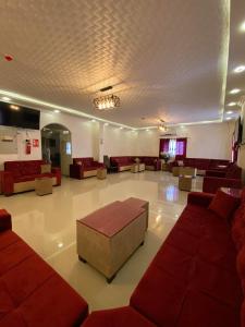 uma grande sala de estar com sofás vermelhos e mesas em فندق وادي القلط em Jericó
