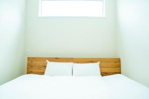 a bedroom with a bed with white sheets and a window at raw_ in Hakuba