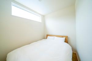 a bedroom with a white bed and a window at raw 白馬唯一屋上露天を独り占めできるデザインコンテナホテル in Hakuba