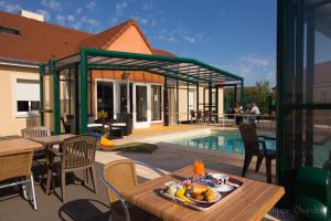 a patio with tables and chairs and a swimming pool at Logis Jum'Hotel in Saints-Geosmes