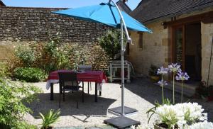 a table with a blue umbrella in a garden at Chambre d'hôtes Auriac du Périgord in Auriac-du-Périgord