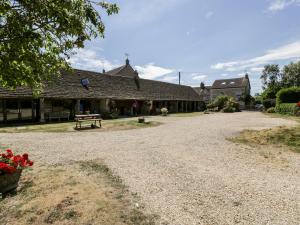 a gravel road in front of a building with a bench at Tinkley Cottage in Nympsfield