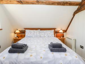 a bedroom with a bed with two towels on it at Tinkley Cottage in Nympsfield