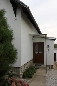 a small white house with a brown door at Domek u lesa in Bítov