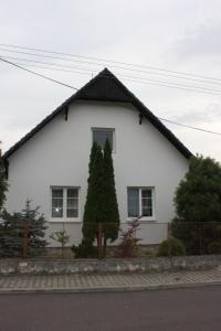 a white house with a black roof at Domek u lesa in Bítov