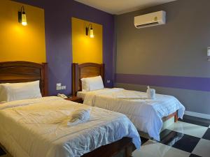 duas camas num quarto com paredes roxas e amarelas em The Palm Resort Kampeang Saen em Nakhon Pathom