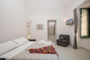 a white bedroom with a bed and a chair at Amalfi 90 - holiday house close the beach in Atrani