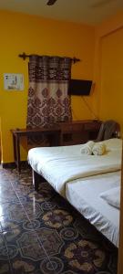 two beds in a room with a curtain and a table at selfia guest house majorda in Majorda