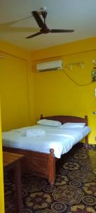 a bed in a yellow room with a ceiling fan at selfia guest house majorda in Majorda