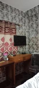 a bedroom with a desk with a monitor on a brick wall at selfia guest house majorda in Majorda