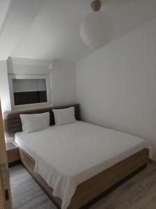 Un dormitorio con una cama blanca con un televisor en la pared. en Apartmani.Sutomore, en Sutomore