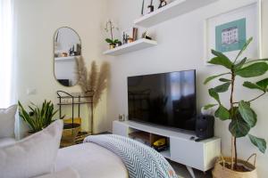 a living room with a tv and a white couch at The Alexander Apartment in Tel Aviv