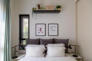 a bedroom with a bed with white sheets and pillows at The Alexander Apartment in Tel Aviv