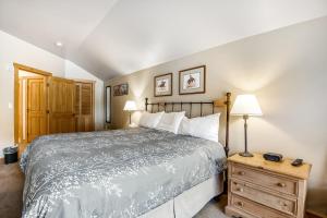 a bedroom with a bed and a wooden dresser with two lamps at Copper Springs in Copper Mountain
