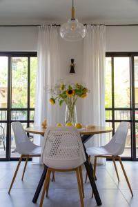 a dining room table with chairs and a vase of flowers at The Alexander Apartment in Tel Aviv