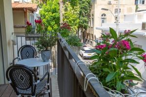 a balcony with a table and chairs and flowers at The Alexander Apartment in Tel Aviv