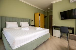 a bedroom with a large bed and a television at Buxus Hotel Shekvetili in Shekvetili