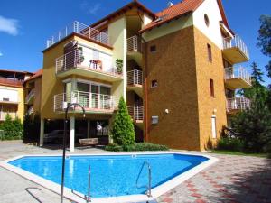 a building with a swimming pool in front of a building at Siófoki Beach Apartman in Siófok