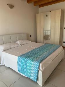 uma grande cama branca com um cobertor azul em LA CASA DI MARTINA em Castelnuovo del Garda