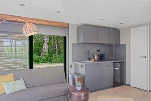 a living room with a couch and a kitchen at Waterlodges WeidumerHout in Weidum