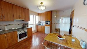 una cocina con armarios de madera y una mesa con un bol de fruta en Casa Todo Verde-A Murcia Holiday Rentals Property, en Los Alcázares