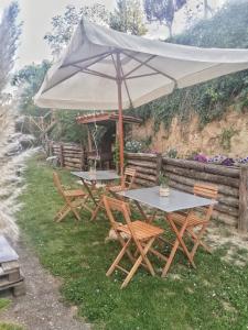 two tables and chairs under an umbrella in the grass at Casa vacanza Flora in Grottazzolina