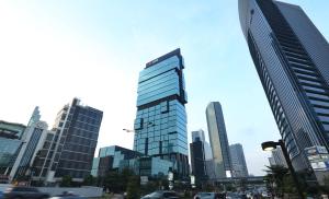 雅加達的住宿－AI Hotel Jakarta Thamrin，城市里一座高大的玻璃建筑,有汽车