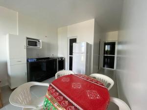 cocina con mesa, sillas y nevera en Condominio Boa Vista en Pontal do Paraná