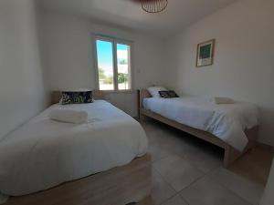 a bedroom with two beds and a window at L'Epicurienne in Simandre