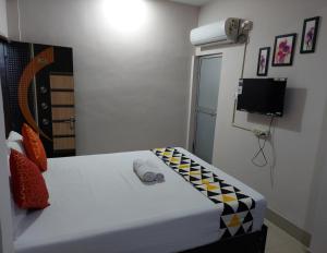 um pequeno quarto com uma cama e uma televisão em Raison Hotel em Jamshedpur