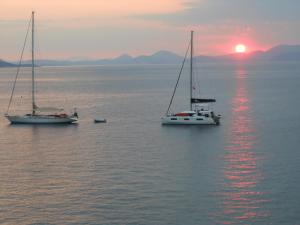 two sailboats in the water with the sunset in the background at HydraVista (Lily) in Hydra