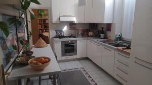 una cucina con armadi bianchi e un cesto di frutta su un bancone di Casa Braglia a Modena