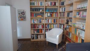 a library with a white chair in front of book shelves at Casa Braglia in Modena