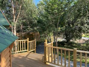 una terraza de madera con una valla de madera y árboles en Craigshannoch Luxury 1 bed woodland lodge hot tub en Kintore