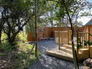 patio trasero con parque infantil de madera y valla en Craigshannoch Luxury 1 bed woodland lodge hot tub en Kintore