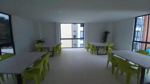 a room with tables and green chairs and windows at Club residencial santafe in Cartago